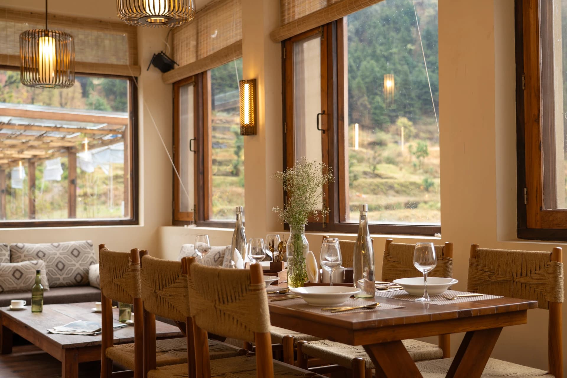 Restaurant interior with woven chairs, wine glasses and mountain views