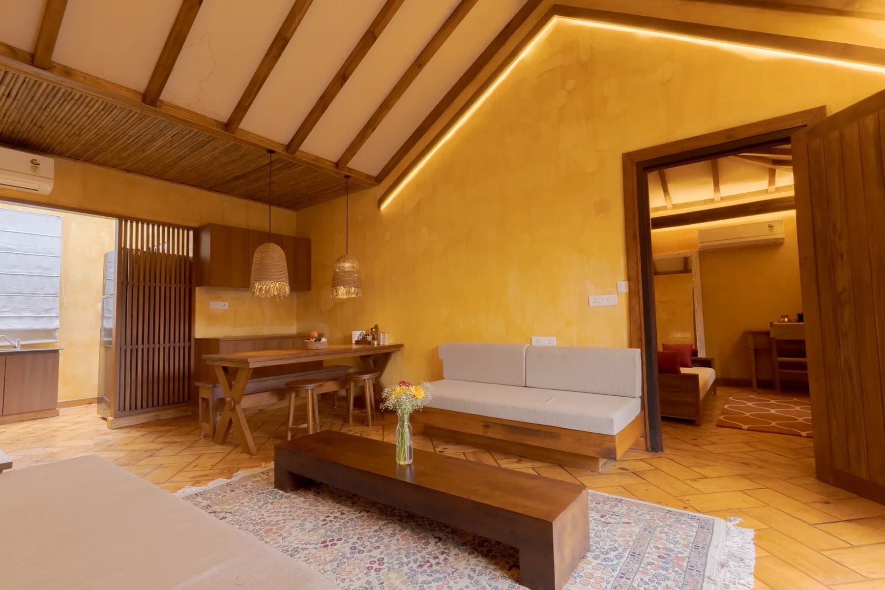 Kaansya villa living room with golden walls, vaulted timber ceiling and mountain-view balcony